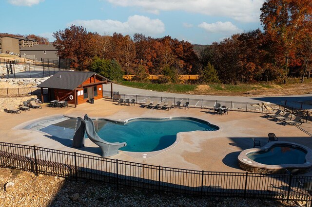 pool with fence, a water slide, and a patio area