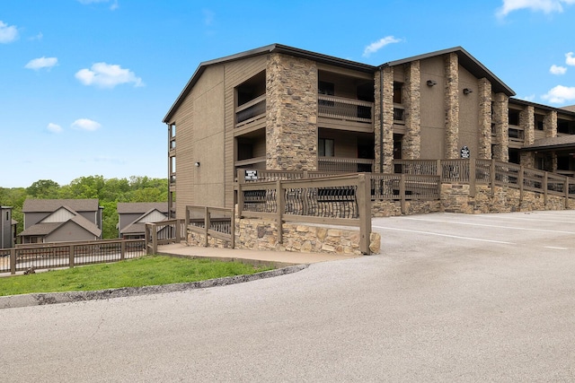 view of property featuring fence and uncovered parking