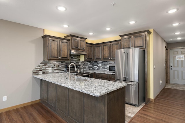 kitchen with a peninsula, baseboards, appliances with stainless steel finishes, and dark brown cabinetry