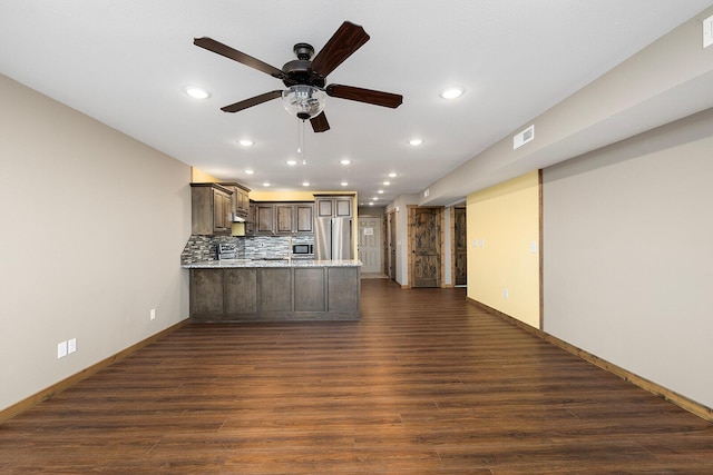 kitchen featuring a ceiling fan, backsplash, freestanding refrigerator, a peninsula, and dark wood-style floors