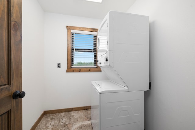 washroom with baseboards, laundry area, stacked washing maching and dryer, and stone finish floor
