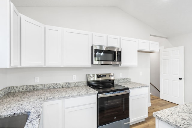 kitchen with stainless steel appliances, white cabinetry, lofted ceiling, and light wood-type flooring