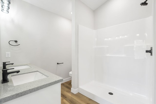 full bath with a walk in shower, a sink, toilet, baseboards, and wood finished floors