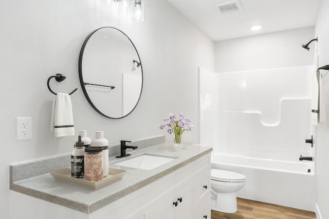 bathroom featuring visible vents, vanity, wood finished floors, toilet, and shower / washtub combination