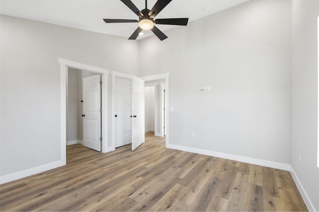 unfurnished bedroom featuring baseboards, a ceiling fan, high vaulted ceiling, and wood finished floors