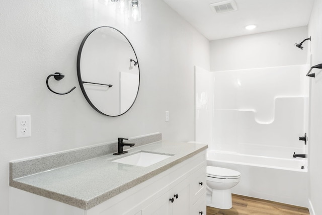 bathroom with shower / bath combination, visible vents, wood finished floors, vanity, and toilet