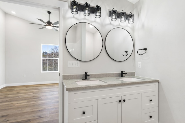 bathroom featuring a sink, ceiling fan, double vanity, and wood finished floors