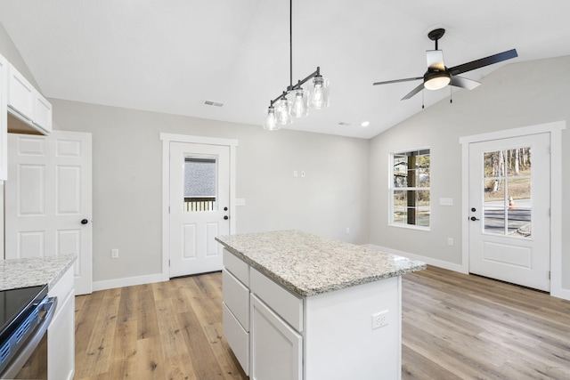 kitchen featuring light wood-style flooring, a ceiling fan, vaulted ceiling, a kitchen island, and visible vents