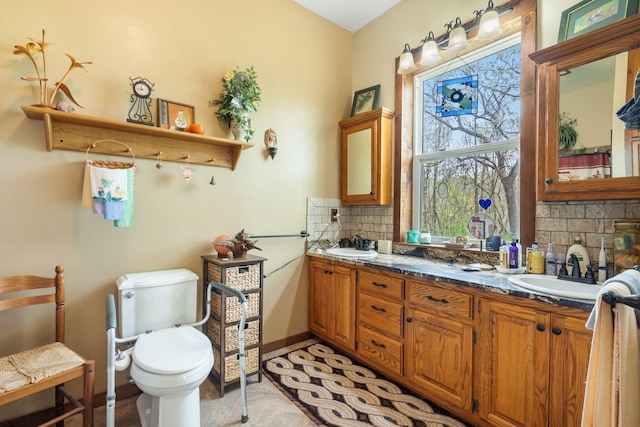 bathroom featuring double vanity, a sink, backsplash, and toilet
