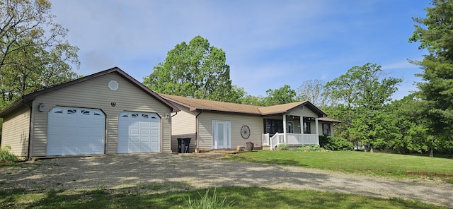 ranch-style house with covered porch, a detached garage, and a front lawn