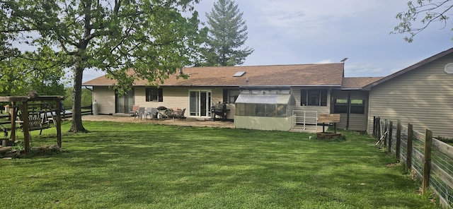 rear view of property featuring fence, a shingled roof, a lawn, and a patio area