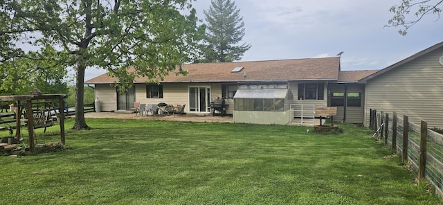 rear view of house featuring a shingled roof, a sunroom, a fenced backyard, a patio, and a yard