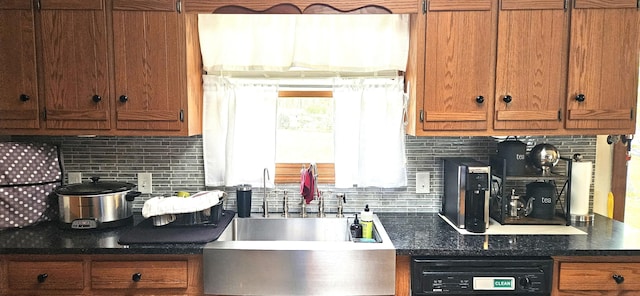 kitchen featuring brown cabinets, dark countertops, tasteful backsplash, and dishwasher