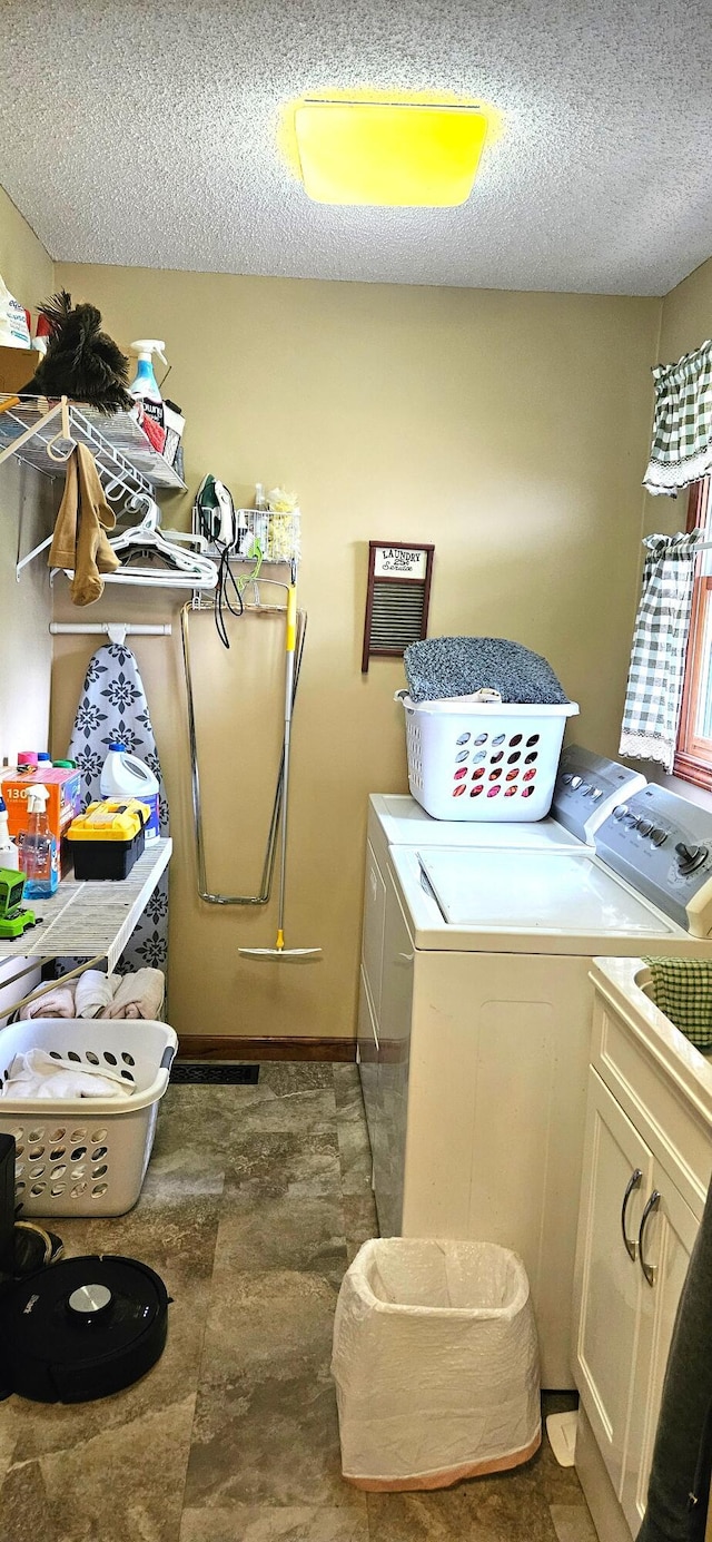 laundry area with washer and clothes dryer, cabinet space, and a textured ceiling
