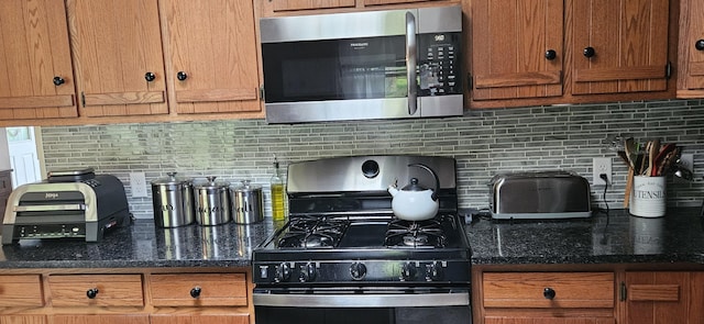 kitchen featuring brown cabinets, black range with gas cooktop, stainless steel microwave, and backsplash
