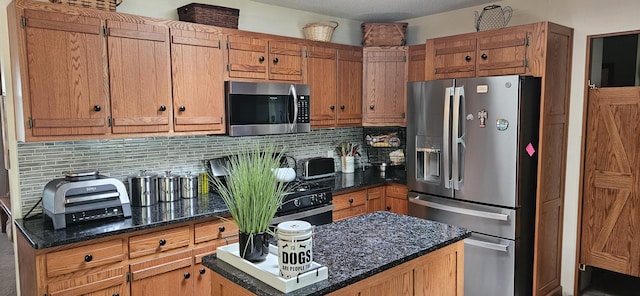 kitchen with dark stone counters, appliances with stainless steel finishes, backsplash, and a kitchen island