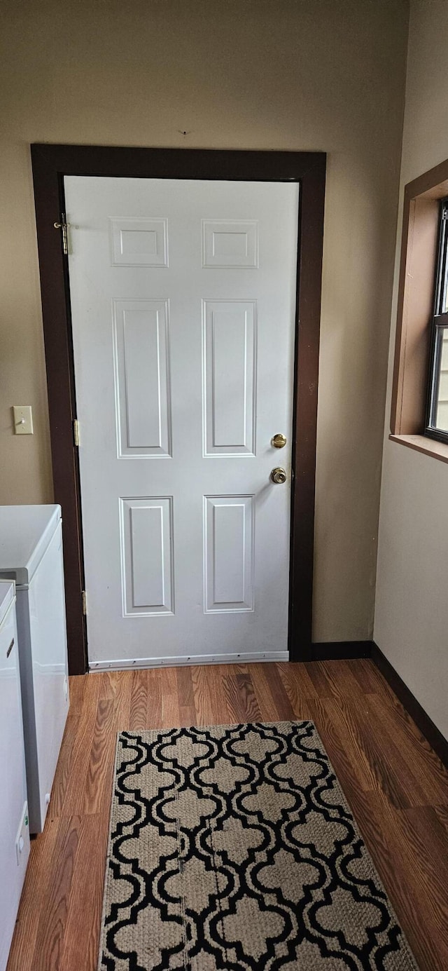 doorway featuring baseboards, wood finished floors, and washing machine and clothes dryer