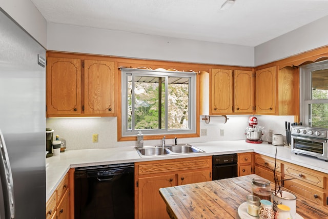 kitchen with stainless steel fridge, a sink, light countertops, black dishwasher, and a toaster