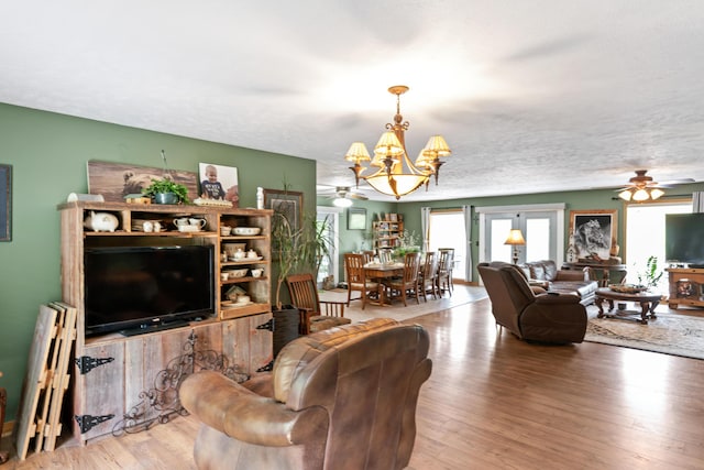 living area featuring ceiling fan with notable chandelier, wood finished floors, and a wealth of natural light