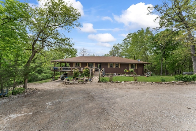 ranch-style home featuring a porch, a front yard, and dirt driveway