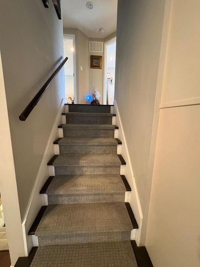 staircase featuring carpet flooring and visible vents