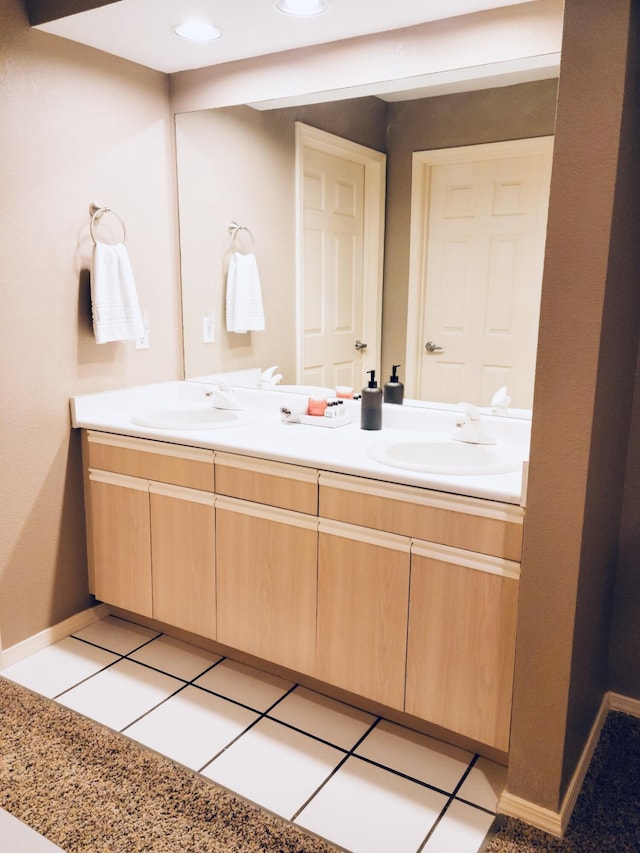 full bath with double vanity, a sink, and baseboards