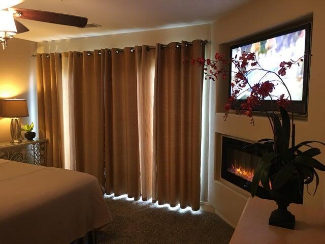 bedroom with a ceiling fan, a glass covered fireplace, and carpet