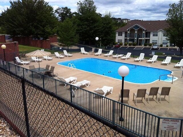 community pool with a patio and fence