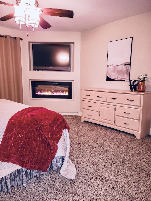 bedroom with a ceiling fan, a glass covered fireplace, and carpet