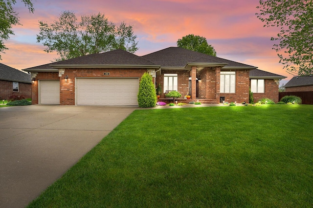 view of front facade featuring brick siding, a garage, a yard, and concrete driveway