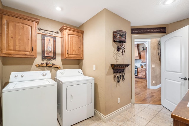 clothes washing area featuring washing machine and dryer, cabinet space, light tile patterned floors, baseboards, and recessed lighting