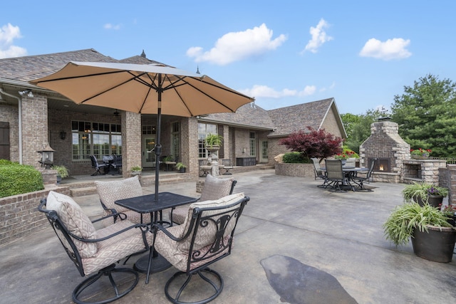 view of patio / terrace featuring outdoor dining space and a warm lit fireplace