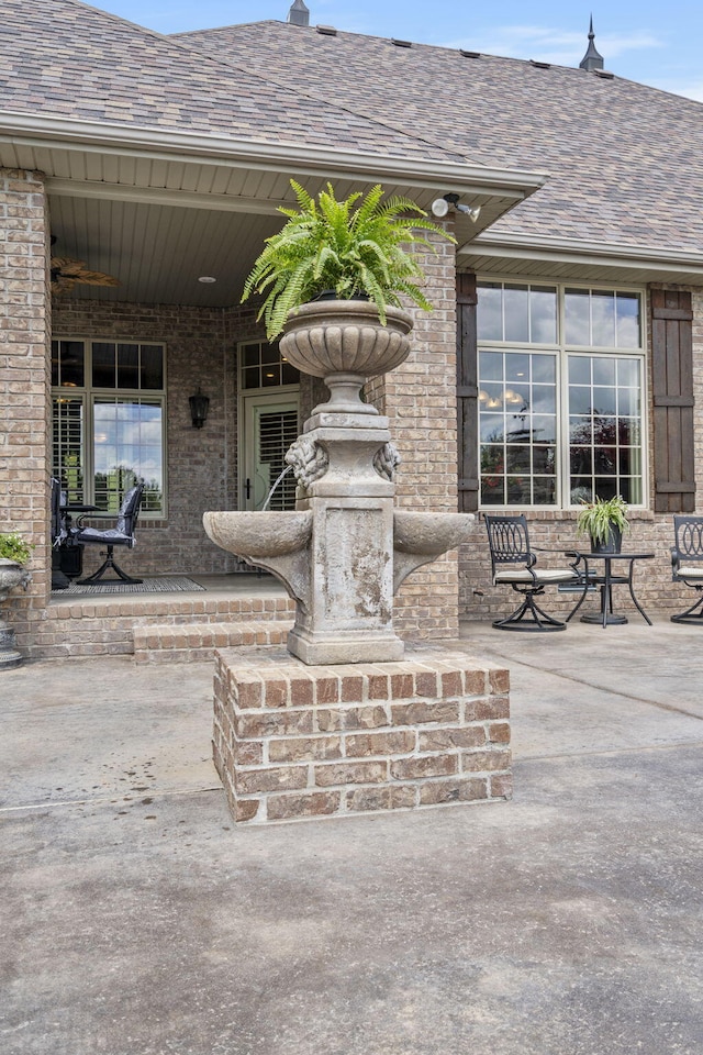 exterior space featuring brick siding and a shingled roof