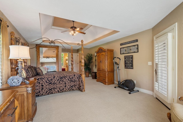 bedroom featuring a raised ceiling, baseboards, light carpet, and a ceiling fan