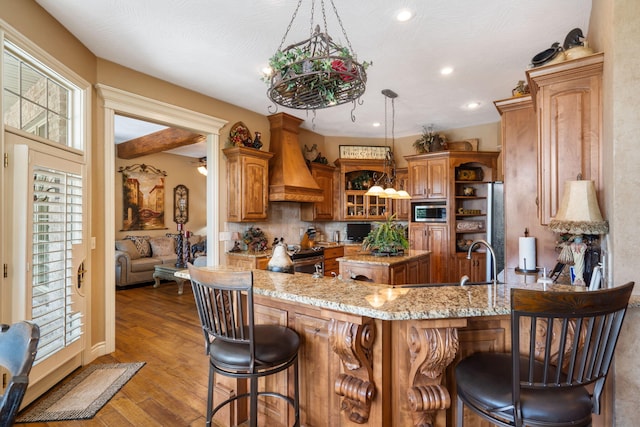 kitchen featuring brown cabinets, a breakfast bar, a center island, stainless steel appliances, and custom range hood