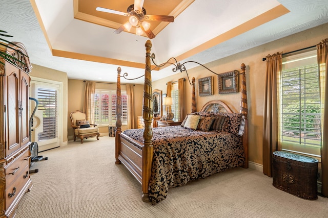 bedroom with baseboards, light colored carpet, access to exterior, and a tray ceiling