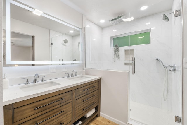 bathroom with a sink, a stall shower, and double vanity