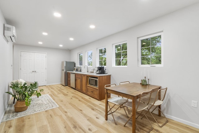 kitchen featuring baseboards, light countertops, brown cabinets, light wood finished floors, and appliances with stainless steel finishes