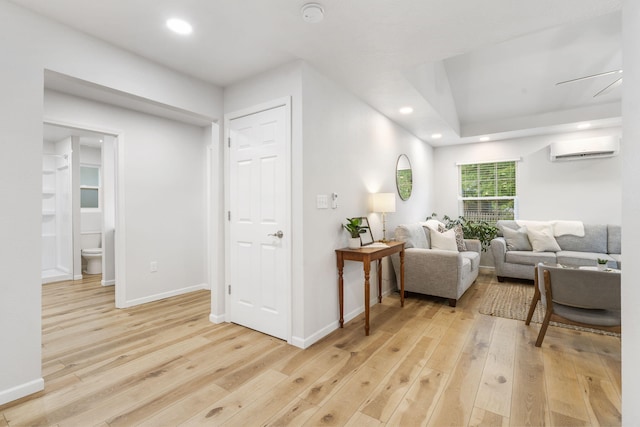 living area featuring recessed lighting, a wall mounted air conditioner, light wood finished floors, and baseboards