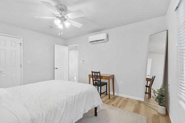bedroom with light wood-style floors, a wall mounted air conditioner, baseboards, and a ceiling fan
