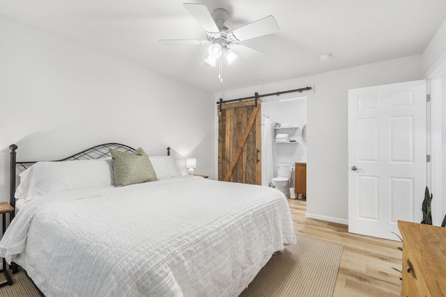 bedroom with light wood-type flooring, a barn door, baseboards, and a ceiling fan