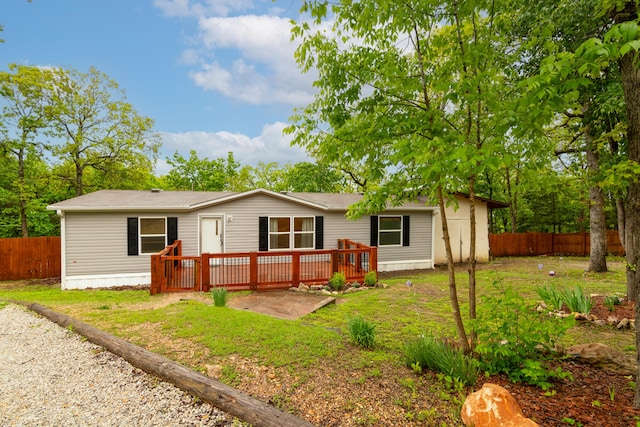back of property with a yard, a deck, and fence