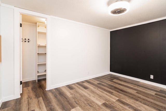 unfurnished bedroom featuring baseboards, wood finished floors, and a spacious closet