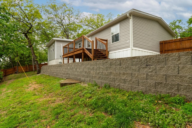 rear view of house featuring a lawn, a fenced backyard, and a deck