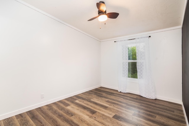 spare room featuring crown molding, baseboards, a ceiling fan, and dark wood-style floors