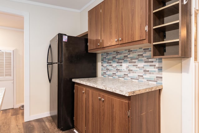 kitchen featuring freestanding refrigerator, decorative backsplash, dark wood-style floors, light countertops, and brown cabinets