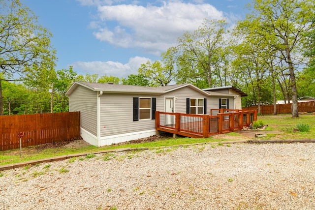 back of house featuring fence, roof with shingles, and a deck