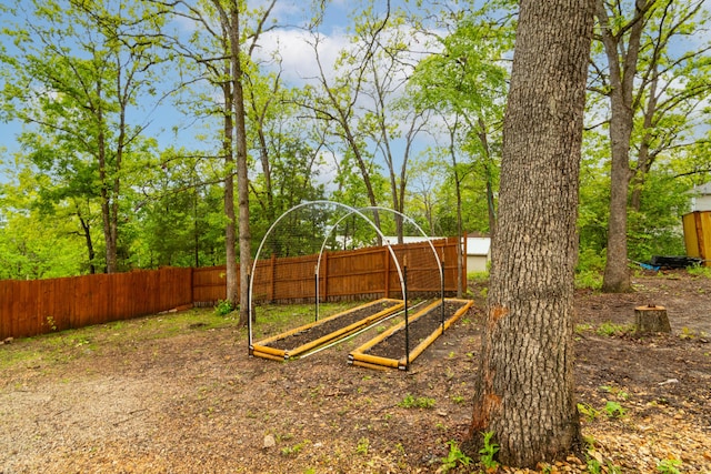 view of play area featuring fence and a vegetable garden