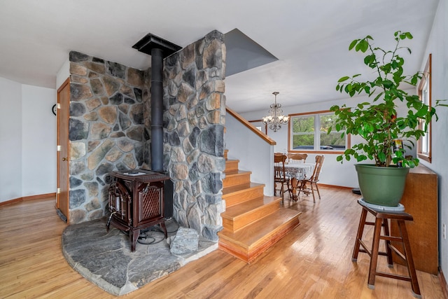 interior space featuring baseboards, an inviting chandelier, wood finished floors, and a wood stove
