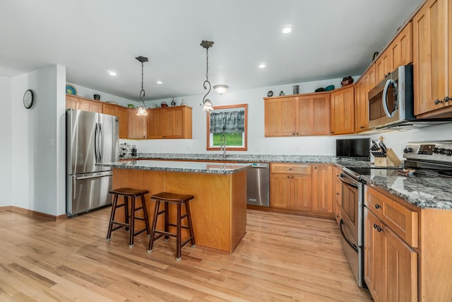 kitchen featuring a center island, light wood finished floors, a kitchen bar, and stainless steel appliances